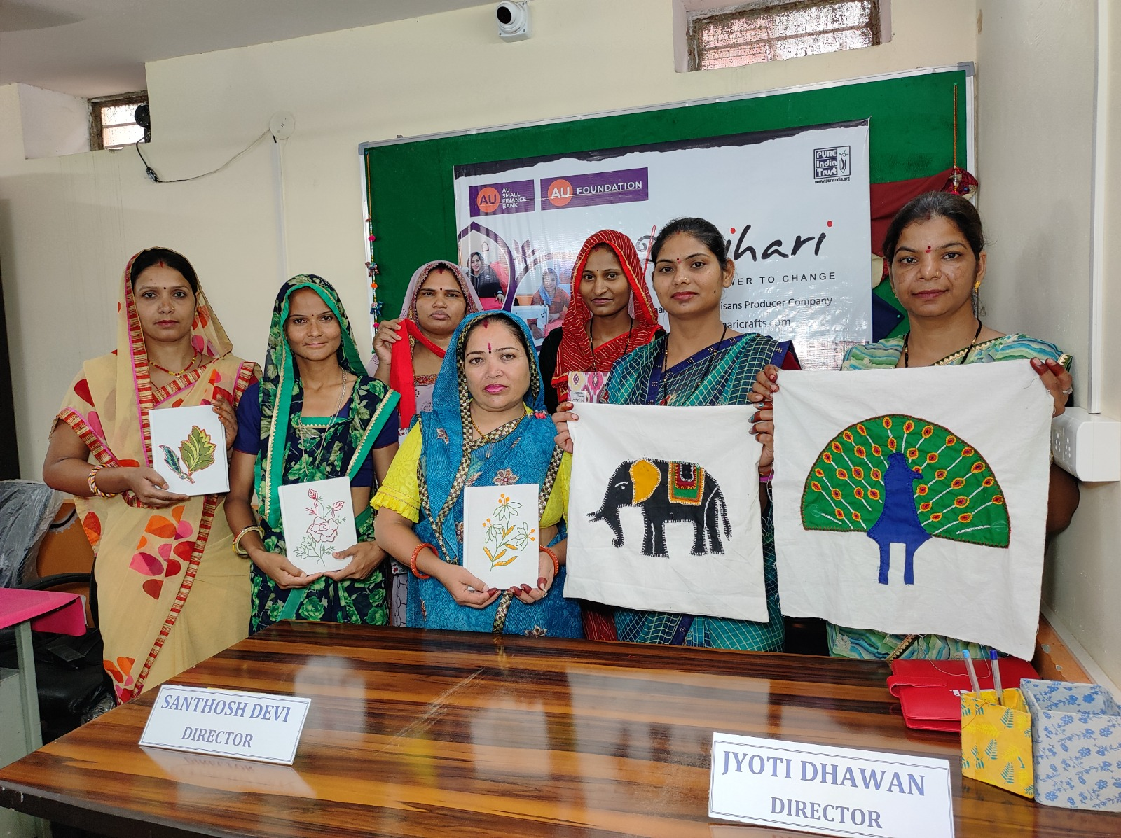 Women artisans displaying hand-embroidered cushion covers they produced