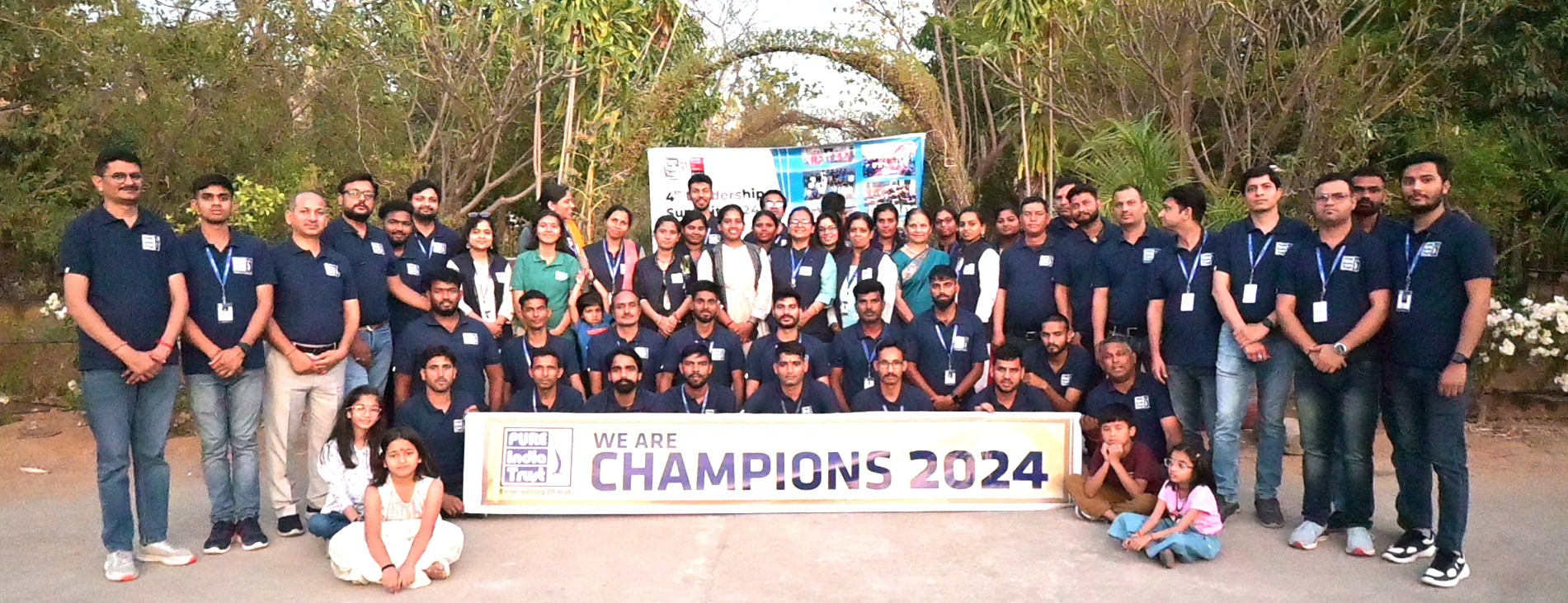 The PURE India Trust team gathered behind a We Are Champions 2024 banner